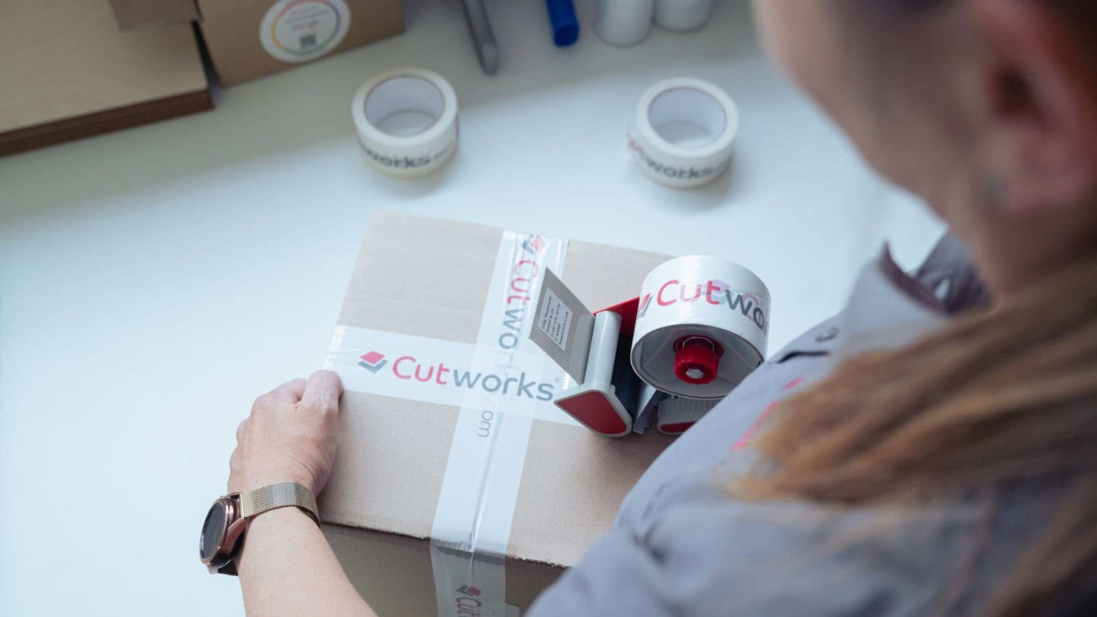 Cutworks – Mitarbeiterin im Versand verpackt Ware